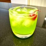 A bright green glass of Midori Sour, a mix of Japanese Midori (a melon liqueur) with lemon and lime.