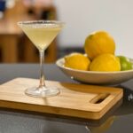 A handmade lemon drop martini posed with bowl of lemons and limes.