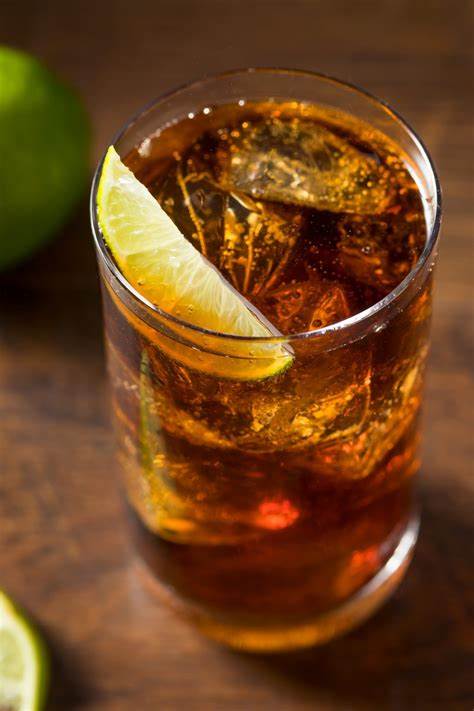 A Cuba Libre, a glass of rum and Coca-cola garnished with a lime wedge.